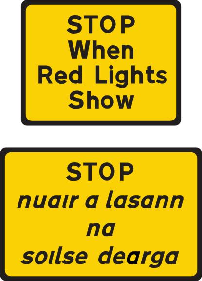 Yellow rectangular plates read STOP When Red Lights Show, with Irish wording below.