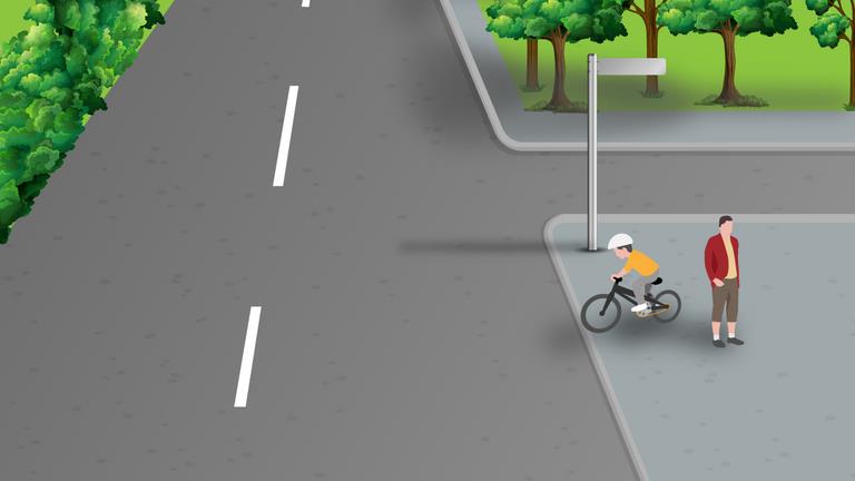 Road junction with an adult and a child on a small bicycle on the right pavement.