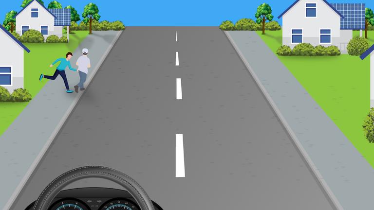 Residential road with two people near the left pavement and houses on both sides.