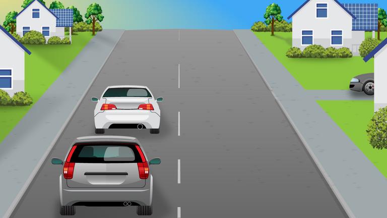 Two cars ahead on a residential road, with another car partly visible at a side road on the right.