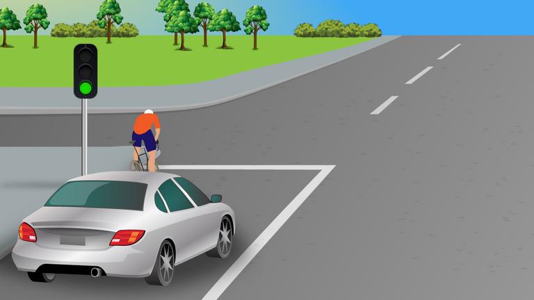 Silver car near a pedestrian crossing; a pedestrian is crossing ahead and a traffic signal shows green.