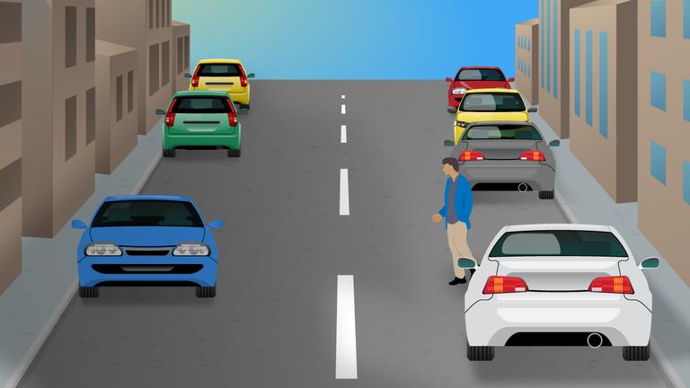 Driver's view along a narrow street with parked cars on both sides and a blue car ahead on the left.