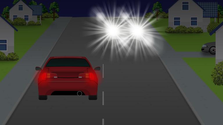 Night view following a red car, with bright oncoming headlights farther ahead.