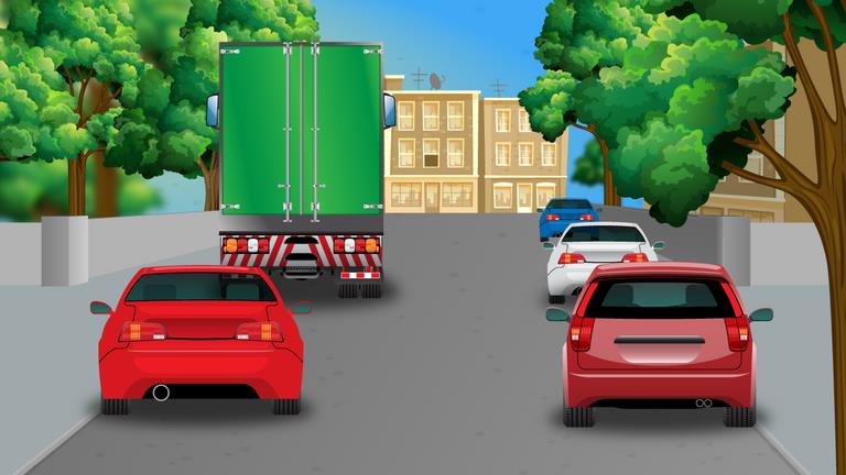 Large green lorry ahead, with red cars behind it on both sides and another car farther ahead to the right.