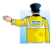 Garda viewed from behind, wearing a yellow jacket and extending one arm horizontally to the left.